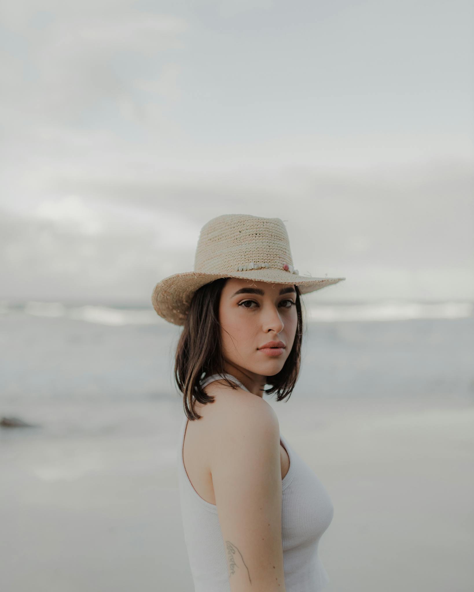A young woman in a sun hat gazes over her shoulder at a beach on the Gold Coast, Australia.