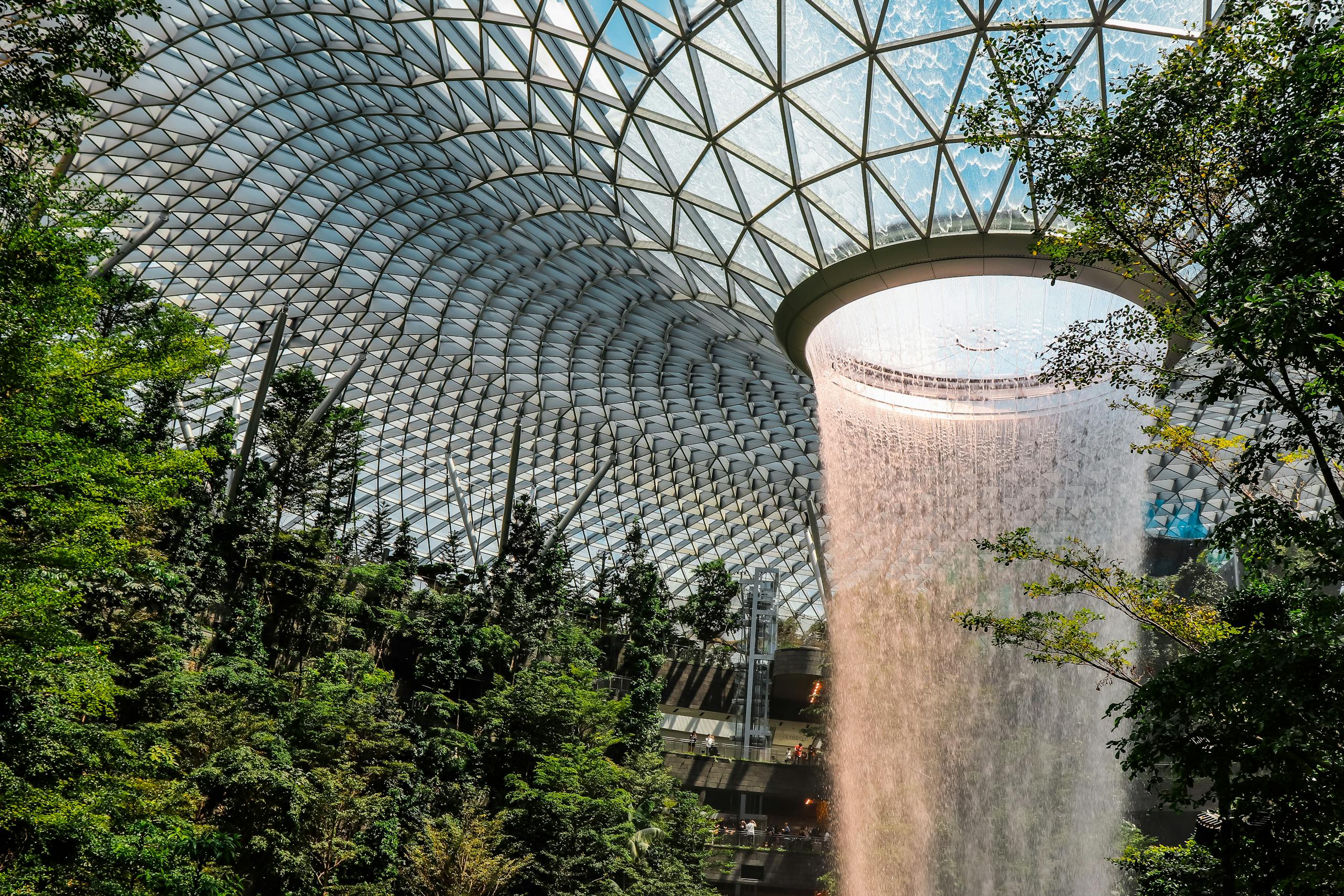 The iconic indoor waterfall at Jewel Changi Airport surrounded by lush gardens.